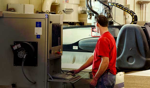 A CNC operator standing next to an industrial CNC machine